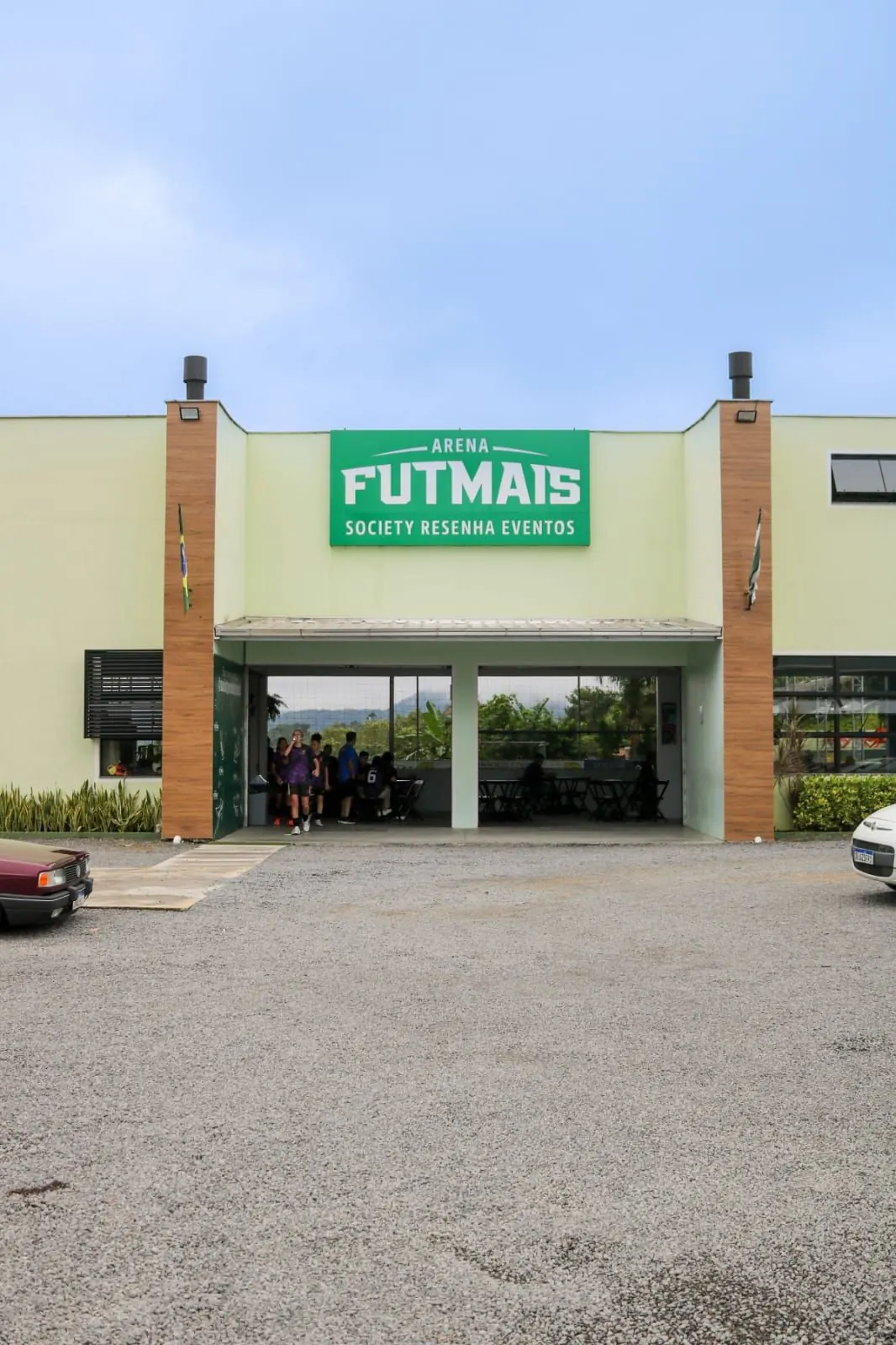 Fachada da Arena Futmais com o letreiro verde “Society Resenha Eventos” e a entrada coberta