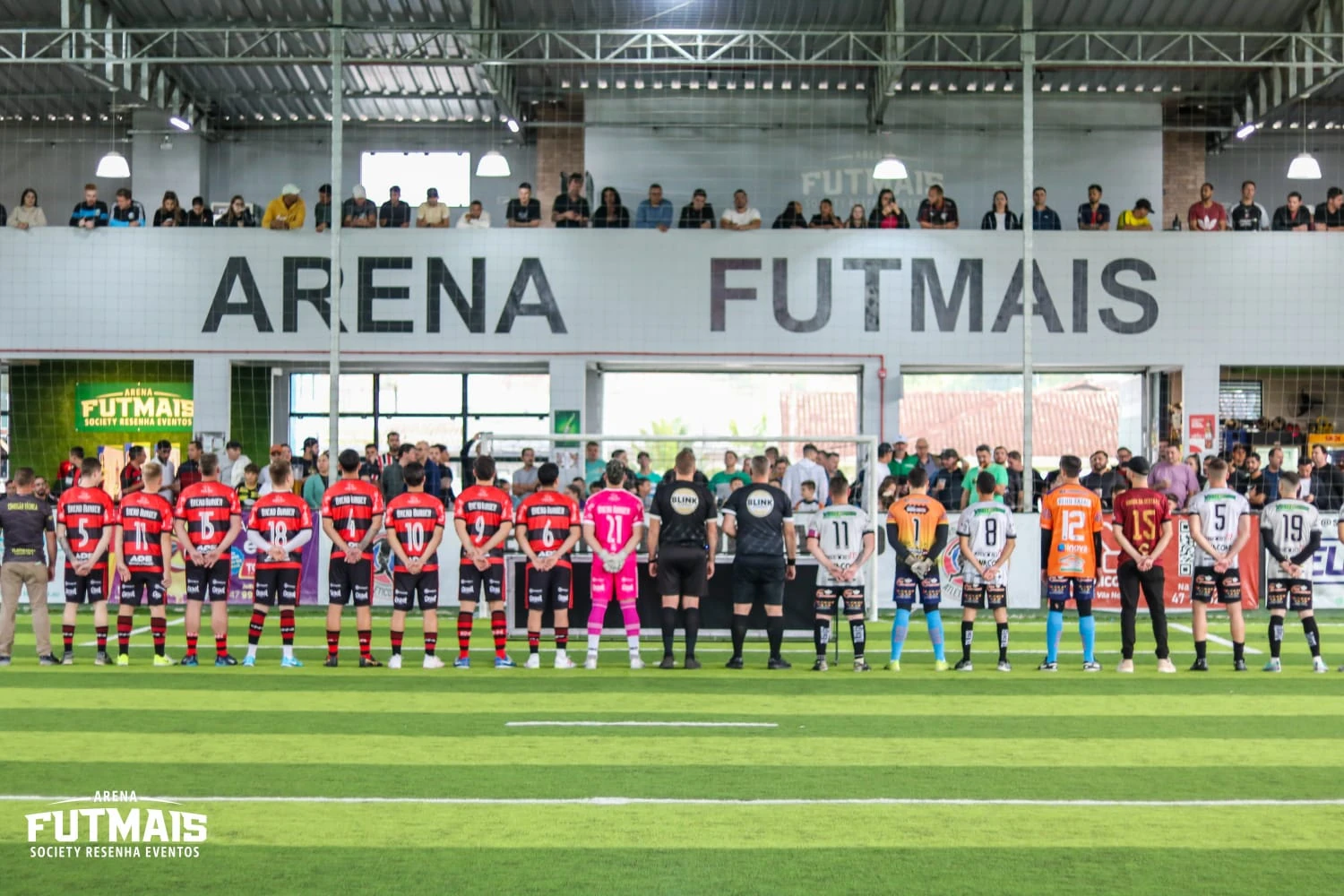 Equipes alinhadas na quadra da Arena Futmais antes de uma partida, com a torcida no mezanino